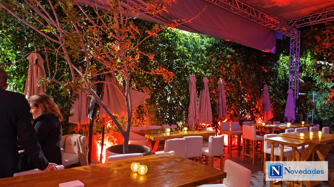 Terraza con mesas, vegetación y luces durante la apertura en Lago Algo